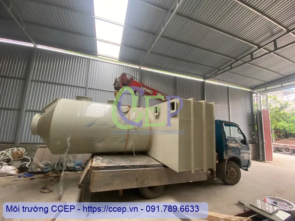 Một tháp hấp thụ xử lý khí thải lớn đang được cần cẩu xếp lên xe tải.